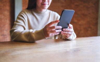 Closeup image of a woman holding and using mobile phone