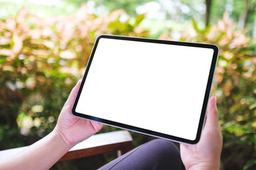Mockup image of a woman holding digital tablet with blank white desktop screen in the outdoors