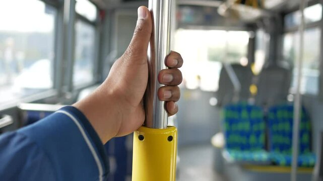 A passengers perspective while holding a metal pole on a city bus during the ride