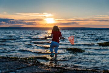 a girl with a net at sunset by the sea of the Volga river
