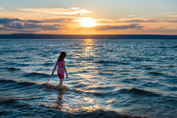 a girl with a net at sunset by the sea of the Volga river