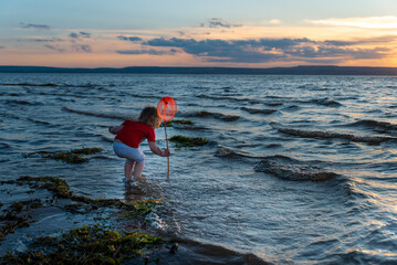 a girl with a net at sunset by the sea of the Volga river