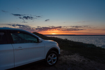a white car at sunset by the sea