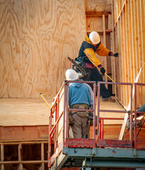 Construction workers measuring an area of wood framing at a construction site