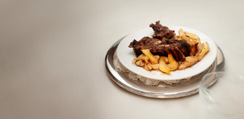 Easter meal featuring tender lamb and potatoes on a white plate and tablecloth, perfect for a festive gathering.
