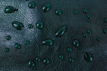 Irregular water drops on black green leather texture, side view, soft focus macro pattern
