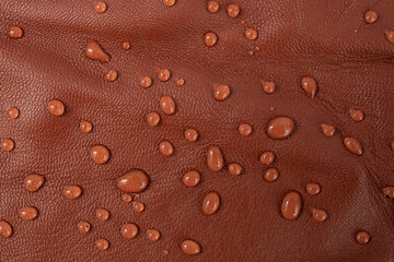 Round water drops on red brown leather texture, top view, soft focus close up abstract pattern