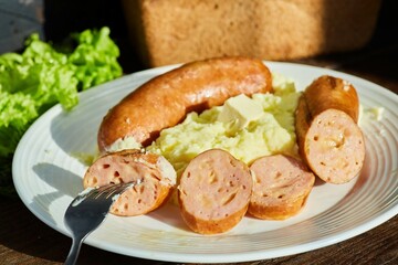 Sausages with cheese in the composition are on a plate with mashed potatoes. Meat lunch, an everyday dish
