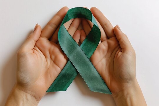 Green handmade awareness paper ribbon on white background.