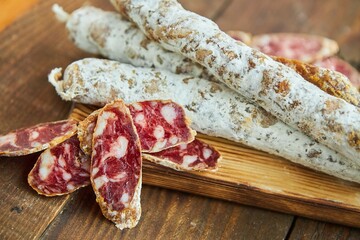 The cured sausage with lard, cut into slices, lies on a wooden surface surrounded by spices. Meat production.