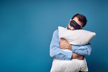 A very sleepy and tired man hugs a pillow on his first day back at work after vacation