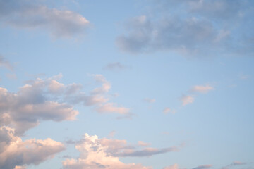 Soft blue sky combined with light of sunset creates peaceful sky. Beautiful landscape with clouds and orange sun. Sky overhead: creamy clouds in pastel colors.