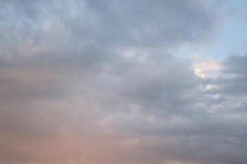 Soft blue sky combined with light of sunset creates peaceful sky. Beautiful landscape with clouds and orange sun. Sky overhead: creamy clouds in pastel colors.