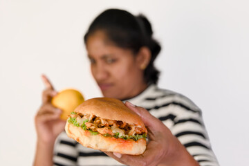 Woman deciding between a burger or apple