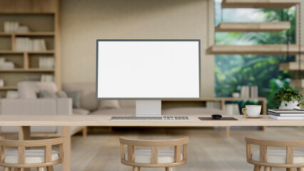 A computer with a white-screen mockup on a wood table in a contemporary and comfortable living room.
