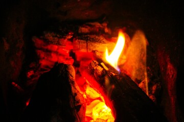 Wooden logs are burning in the fireplace. close-up. Tongues of flame on a dark background.