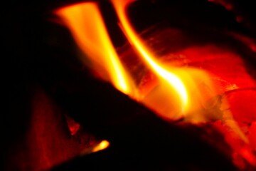 Close-up of burning log in bonfire. Large orange flame from fire with woods. Light and ash from wood in balefire.