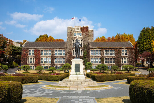 Seodaemun-gu, Seoul, South Korea - October 30, 2022: Autumnal and front view of bronze statue of Underwood against Main building with maple ivy at Yonsei University
