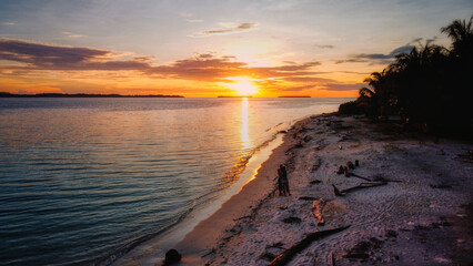 An aerial view of Sumatra's coastline during Sunset, showcasing the stunning contrast between lush tropical forests and vibrant turquoise waters. A paradise waiting to be explored.