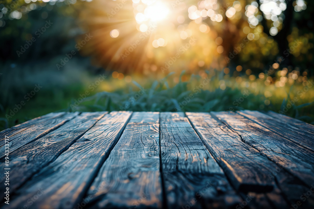 Aufkleber empty wooden table top showing blurred green grass and trees with sun shining through, perfect for p