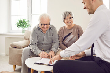 Real estate office realtor helps happy senior couple sign property purchase agreement. Contract...