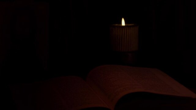 An Open Bible And A Burning Candle In The Church. The Icon Of Jesus Christ Can Be Seen In The Background.
