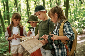 Paper traditional map. Kids in forest at summer daytime together