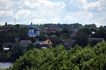 Fototapeta premium church. view of the Ukrainian church in the village. religion, Christianity. church holidays. crosses on the domes. no people. roofs of houses. summer or spring time. Orthodox temple.