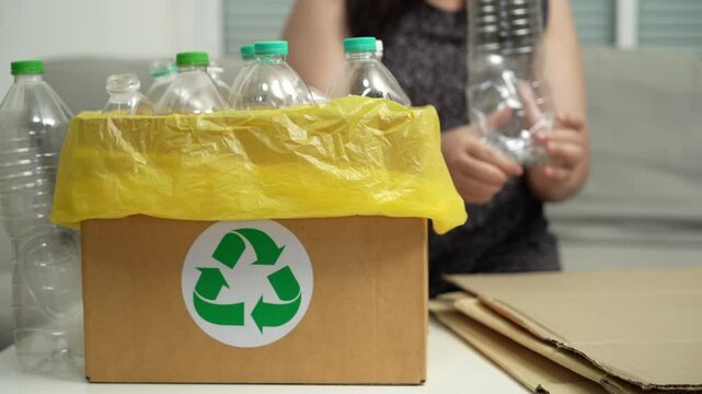Home recycle eco green zero concept Woman throwing empty plastic bottle in recycling bin with yellow garbage bags at home