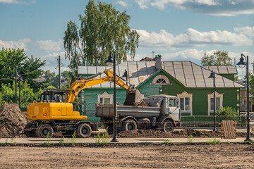 Fototapeta premium Excavator digs soil. Repair and replacement of road surfaces in the city street. City improvement.