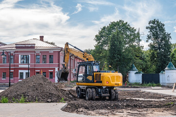 Excavator digs soil. Repair and replacement of road surfaces in the city street. City improvement.