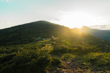 Fototapeta premium landscape, in the forest, mountains, in the background a group of tents in the rays of the sun