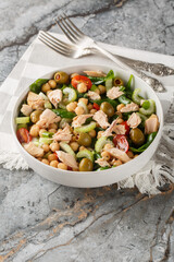 Tuna chickpea salad with tomatoes, spinach, celery dressed with olive oil close-up in a bowl on the table. Vertical