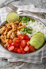 Chicken Carnitas bowl or burrito bowl with rice, tomatoes, jalapeno pepper and avocado close-up on the table. Vertical