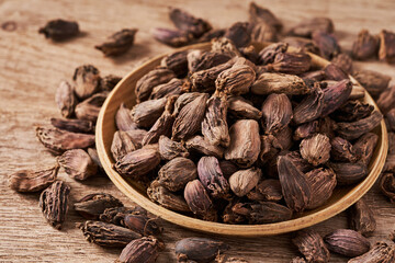 closeup pile of Amomum subulatum or black cardamom on rustic food background in wood bowl