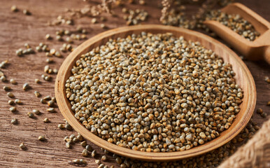 closeup pile of dry bajra pearl millet seed on rustic food background in wood bowl