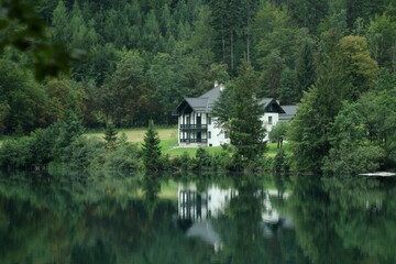 A house by the lake among the tree in Austria Alps