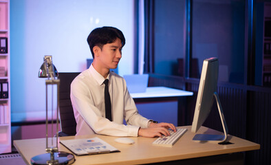 Businessman drinking coffee to get some energy for working overtime sitting at desk using computer and doing overtime