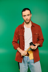 Handsome man in work uniform with camera on green backdrop.