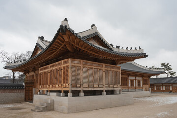 Jongno-gu, Seoul, South Korea - January 29, 2023: Winter view of snow covered yard and tiled house at Gyeongbokgung Palace
