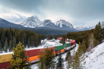 A freight train carrying container passing through the Bow Valley on winter at Morants Curve