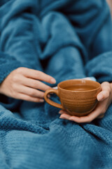 Woman wrapped in blue blanket holding a cup of tea