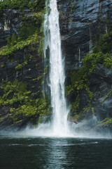 Fototapeta premium Moody waterfall flowing in tropical rainforest at Milford Sound