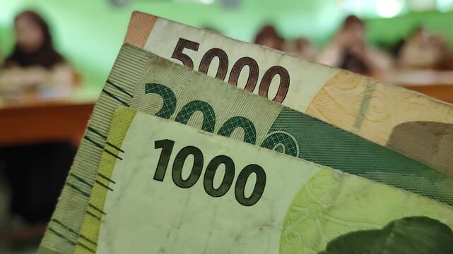 Low nominal money in Indonesian currency with a blurred background of students in class
