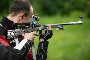 A skilled male athlete engages in free rifle training outdoors, demonstrating his expertise and precision in shooting, known for his dedication and focus in the open-air practice environment.