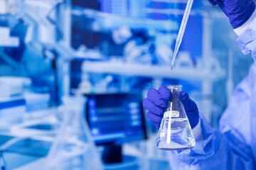 A scientist is holding a beaker filled with a clear liquid. Concept of precision and focus, as the scientist carefully measures and pours the liquid