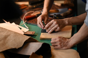 Close up shot two young artisans working with leather in a workshop. Small business and Handmade concept