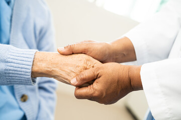 Doctor holding hand and help senior woman patient in hospital.