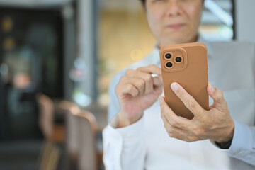 Cropped shot of mature older businessman using mobile phone at office
