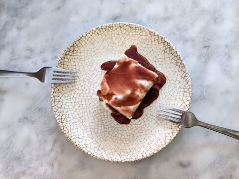 Top view of a plate with a square slice of cheesecake